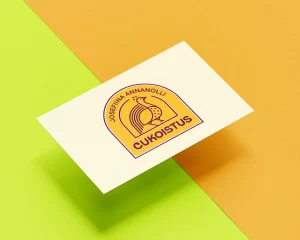 Cukoistuksen logo käyntikorttipohjalla. Logossa on ylväästi ylöspäin katsova riikinkukko, oranssi-purppura värimaailma ja tekstit "Cukoistus" sekä "Josefiina Annanolli".